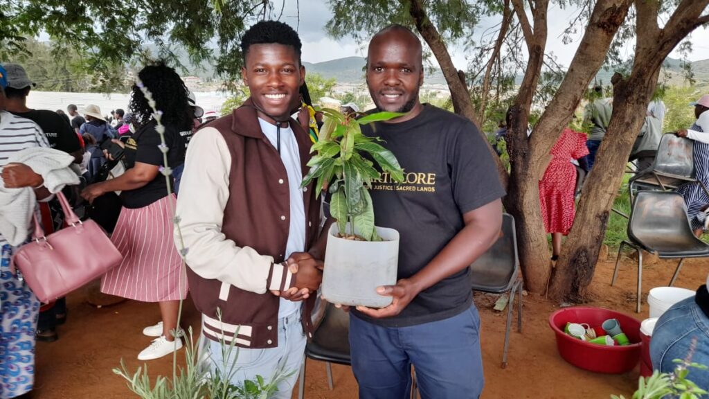 Patric handing a fruit tree to Mxolisi Ngwenya from Enkaba